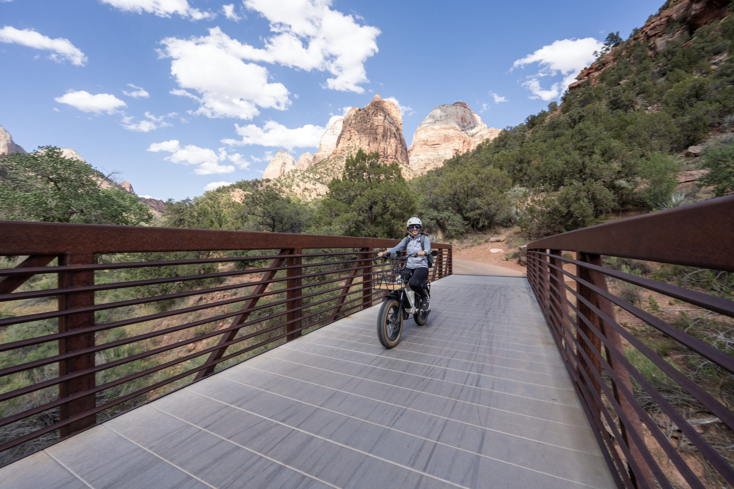 Female E-bike rider crossing a bridge on the Pa'rus trail in Zion National Park.
